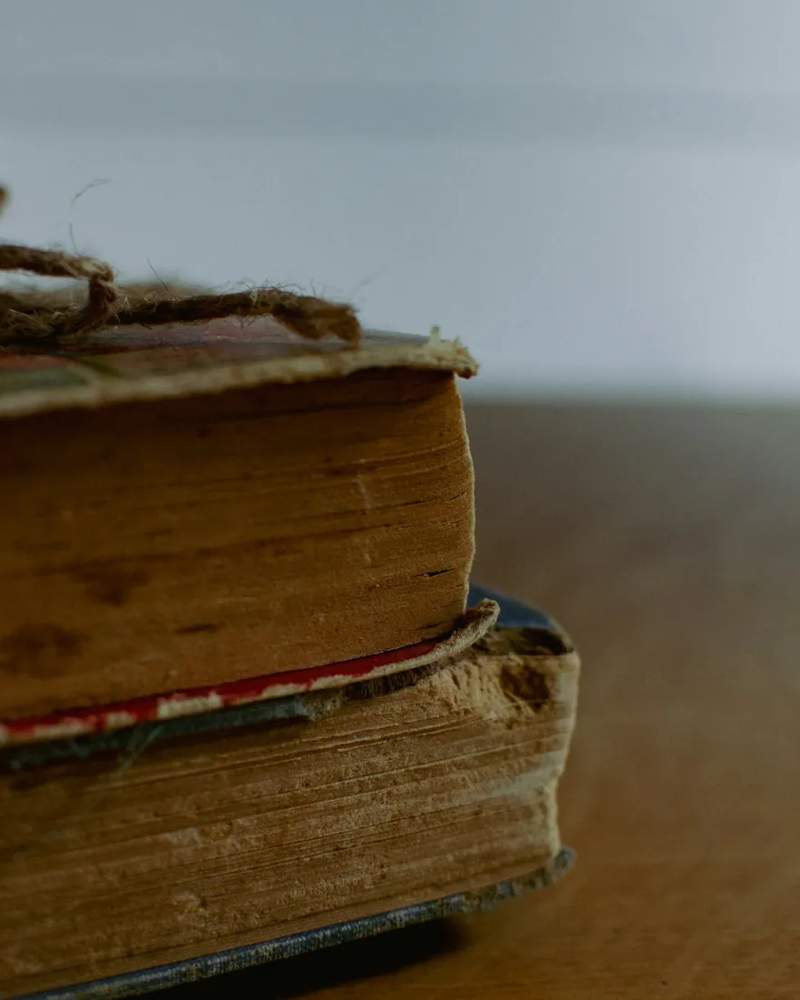 Pila de libros antiguos con lomos gastados sobre una mesa de madera
